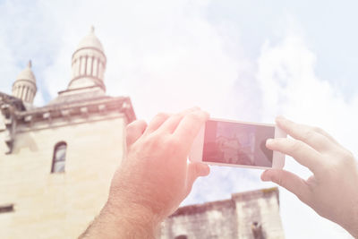 Midsection of person using mobile phone against sky