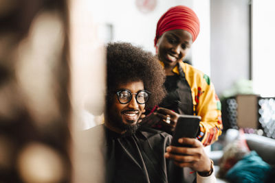 Smiling male customer taking selfie with female barber at hair salon