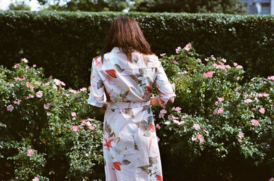 Rear view of woman with flowers against trees