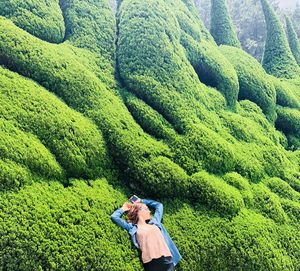 High angle view of woman lying on green mountain