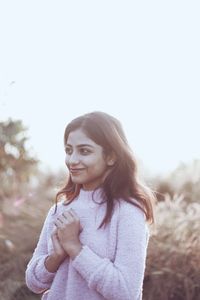 Portrait of young woman standing against clear sky