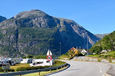 Road leading towards mountains against clear sky