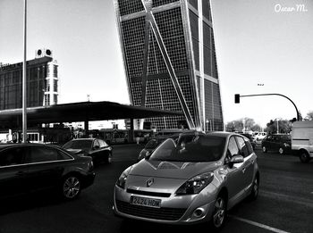 Cars on road by buildings against sky in city