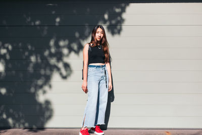 Portrait of woman standing against wall