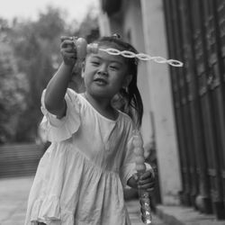 Girl holding toy while standing outdoors