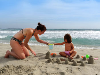 Mother and daughter making sandcastles at beach