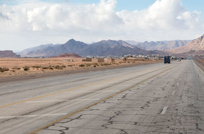 Scenic view of road by mountains against sky