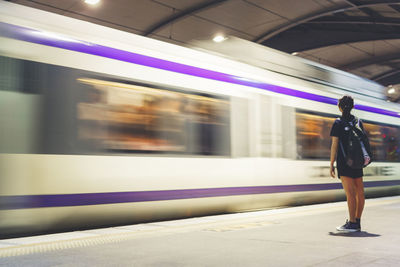 Woman standing by blurred train at subway station