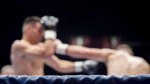 Boxers fighting in boxing ring at stadium