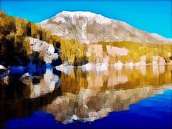 Scenic view of lake by mountain against blue sky