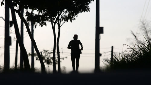 Rear view of silhouette man standing on field against sky