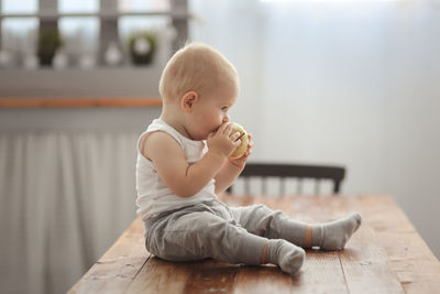Baby with an apple in the kitchen in a real interior. the concept of a healthy childhood, mom's love