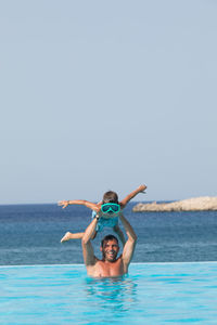 Portrait of young man in swimming pool against sea