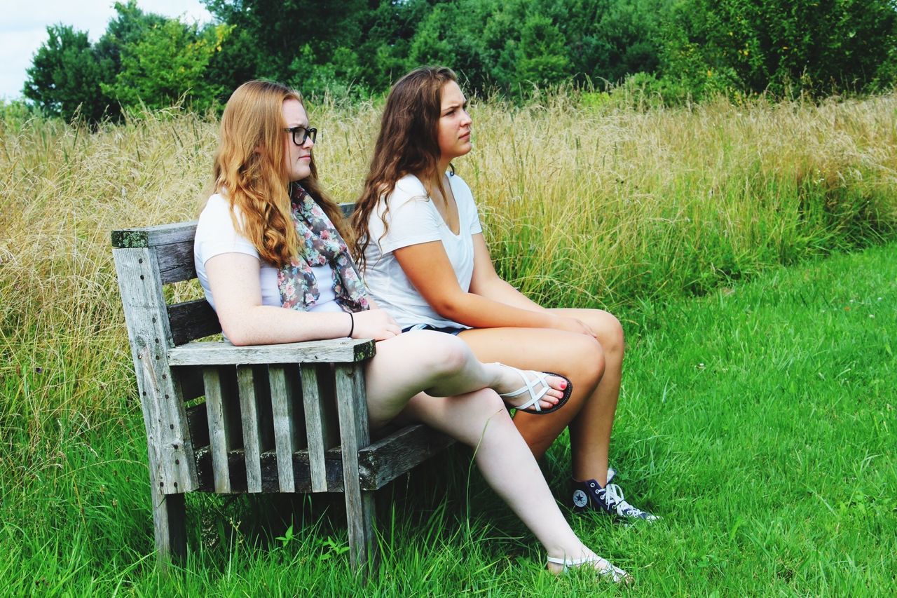 grass, lifestyles, person, leisure activity, full length, young adult, casual clothing, sitting, childhood, young women, relaxation, field, grassy, park - man made space, tree, elementary age, three quarter length, green color