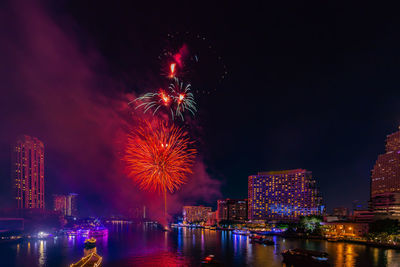 Firework display over illuminated buildings in city at night