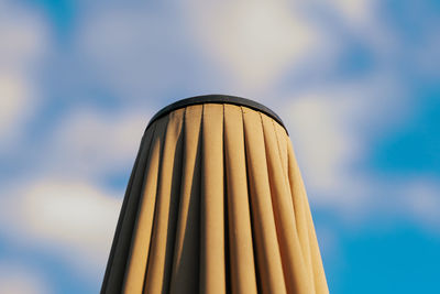 Closed top of parasol against cloudy sky