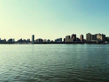 Sea by buildings against clear sky