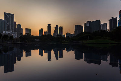 Reflection of buildings in lake against sky during sunset