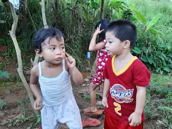 High angle view of cute girl and boy talking at each other in a field.