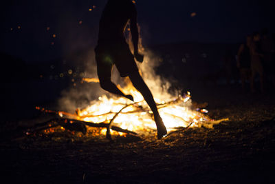 Low section of man with fire on field at night