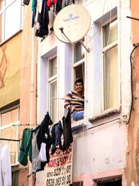 Low angle view of woman hanging outside building