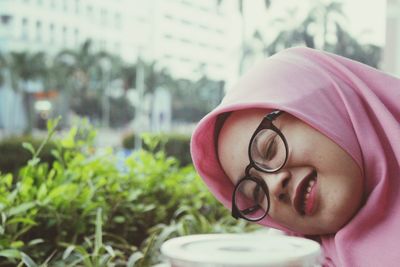 Close-up portrait of woman winking against plants