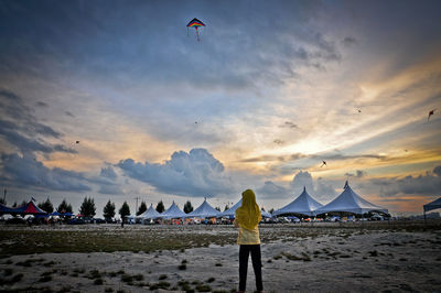 Rear view of woman on sand against sky during sunset