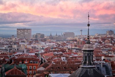 Aerial view of buildings in city against cloudy sky