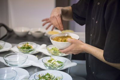 Midsection of man preparing food in bowl on table