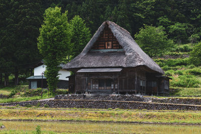 Abandoned house on field against trees