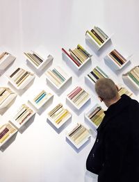 Tilt shot of man looking at bookshelves on white wall