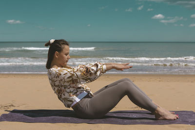 Female athlete performing pilates exercise on the beach
