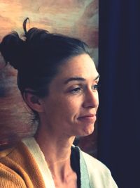 Close-up portrait of young woman looking away at home