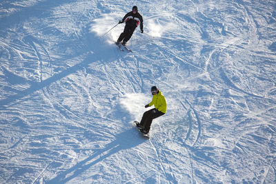 High angle view of people skiing and snowboarding on snow