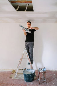 Portrait of young man working on wall