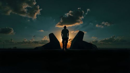 Silhouette woman standing by sea against sky during sunset