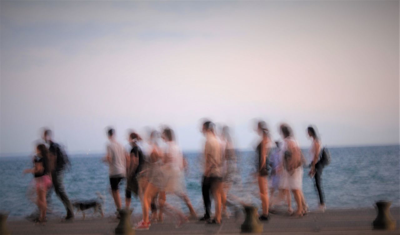 PEOPLE WALKING ON BEACH AGAINST SKY