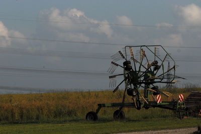 Haymaking agricultural machinery at farm against sky