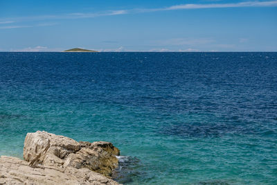 Rock formation in sea against blue sky