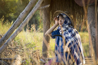 Side view of girl standing in thatched hut