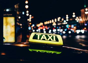 Close-up of illuminated taxi sign on car at night