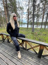 Young woman sitting on railing in forest