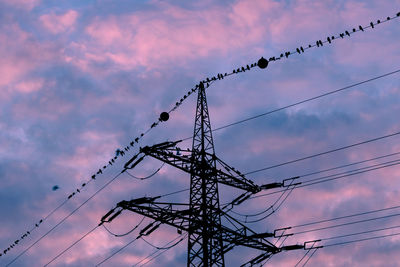 Low angle view of electricity pylon against sky during sunset