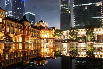 Reflection of buildings in puddle at night