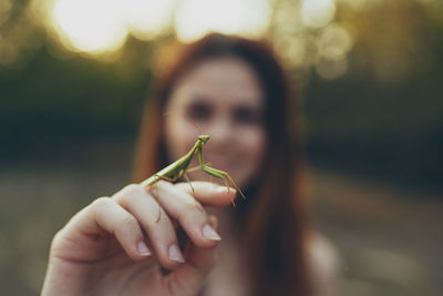 Close-up of woman holding insect against blurred background