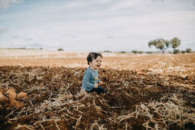 Child sittind on plowed field smiling