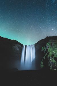 Scenic view of waterfall against sky at night