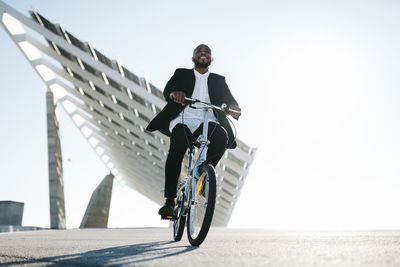 Businessman riding bicycle at solar panels