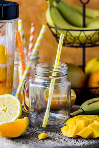 An empty glass jar mug surrounded by ingredients to make a mango citrus smoothie