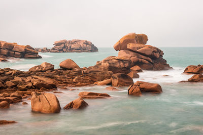 Rocks on sea shore against sky